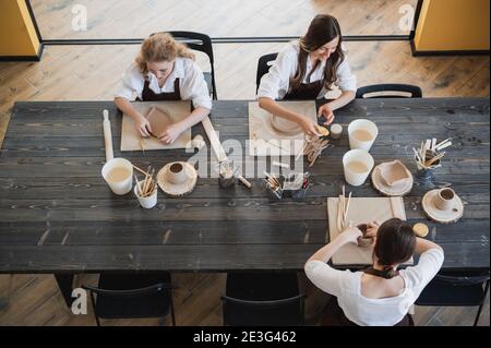 Young women learning to sculpt with a clay during a lesson at workshop in art studio. Stock Photo