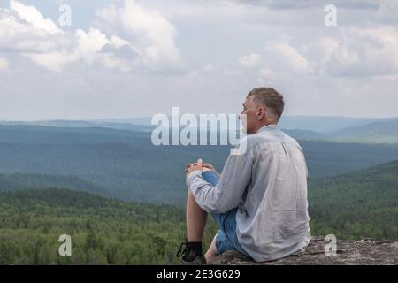 A free middle-aged man enjoying beautiful view of the mountain valley. Healthy lifestyle and travel concept. Loneliness, unity with nature. Copy space Stock Photo