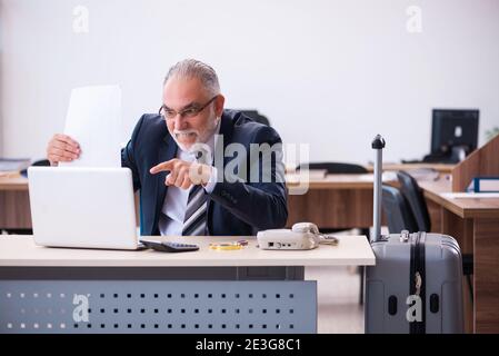 Aged male employee preparing for travel in the office Stock Photo