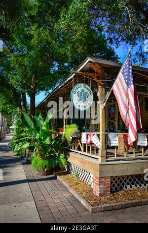 American flag hangs  alongside The Green turtle Tavern round logo sign welcoming patrons to their outdoor dining area alongside tropical plants and lo Stock Photo