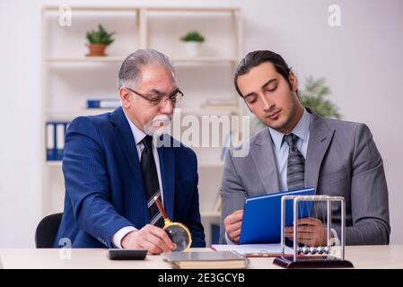 Two businessmen and meditation balls on table Stock Photo