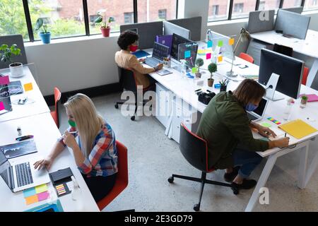 Diverse group of business people wearing face masks in creative office Stock Photo