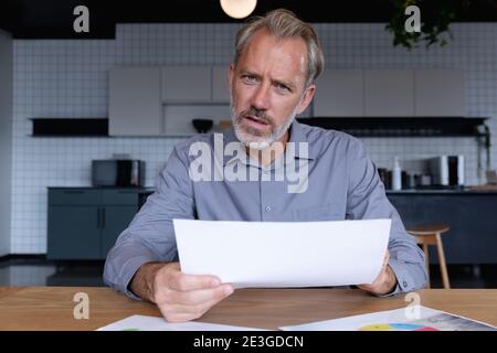 Caucasian businessman sitting having video chat going through paperwork in modern office Stock Photo