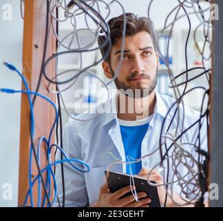 The electrician trying to untangle wires in repair concept Stock Photo