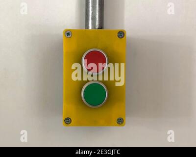 Alarm switch with red and green buttons against blank wall Stock Photo