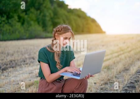 Woman farmer smart farming standing farmland smiling using laptop Female agronomist specialist research monitoring analysis data agribusiness Caucasia Stock Photo