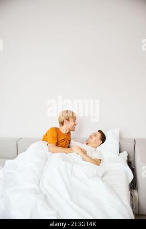 Happy gay couple resting in bed at home Stock Photo