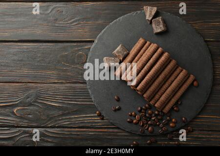 Tray with chocolate wafer rolls, coffee beans and chocolate on wooden background Stock Photo