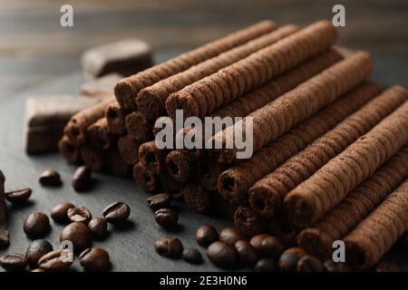 Tray with chocolate wafer rolls, coffee beans and chocolate, close up Stock Photo