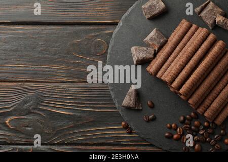 Tray with chocolate wafer rolls, coffee beans and chocolate on wooden background Stock Photo