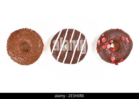 Three chocolate glazed cookies with different toppics in a row on white background Stock Photo