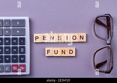 Words pension fund with calculator and glasses on desk. Stock Photo