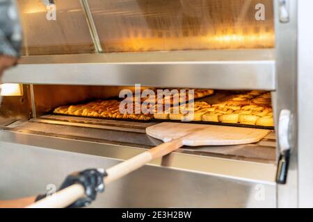 The baker carries a tray of rice cake in his hands and is putting it in the bakery's oven Stock Photo