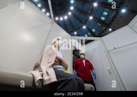 Frankfurt, Germany. 19th Jan, 2021. 19 January 2021, Hessen, Frankfurt/Main: 90-year-old Odores H. waits in a vaccination booth under the domed roof of the vaccination centre in the Festhalle in Frankfurt for her vaccination against the novel coronavirus. This is where thousands of people usually gather at concerts and trade fairs, and where the state of Hesse operates one of its vaccination centres. On the first day of regular operation, around 500 people are to be vaccinated against Corona here. Photo: Boris Roessler/dpa Pool/dpa Credit: dpa picture alliance/Alamy Live News Stock Photo