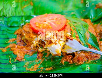 Closeup of banana leaf fried fish taken on a fork to be eaten. A true Kerala style preparation, this spicy meen pollichathu. Stock Photo