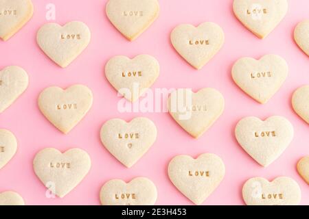 Heart shaped cookie mosaic with the word LOVE on a pink background. Valentine's Day, Mother's Day, anniversary. Top view. Stock Photo