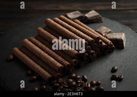 Tray with chocolate wafer rolls, coffee beans and chocolate on wooden background Stock Photo
