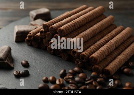 Tray with chocolate wafer rolls, coffee beans and chocolate on wooden background Stock Photo