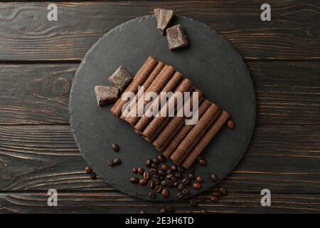 Tray with chocolate wafer rolls, coffee beans and chocolate on wooden background Stock Photo
