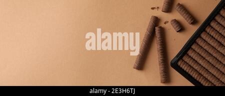 Plastic box with chocolate wafer rolls on brown background Stock Photo