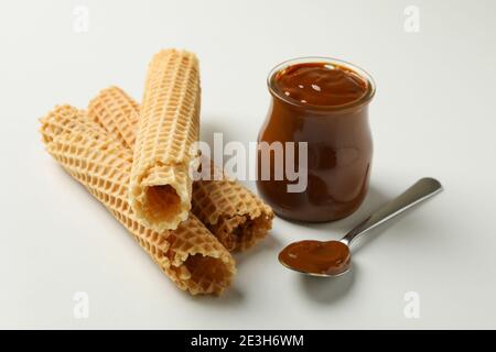 Jar of delicious wafer rolls with boiled condensed milk on tile ...
