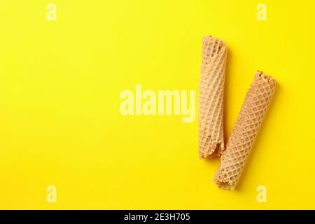 Tasty wafer rolls with condensed milk on yellow background Stock Photo