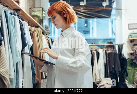 Young woman in a store using a digital tablet. Fashion store owner using tablet computer. Stock Photo