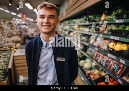 Portrait of young hypermarket worker smiling at camera. Man on a holiday job in a supermarket. Stock Photo