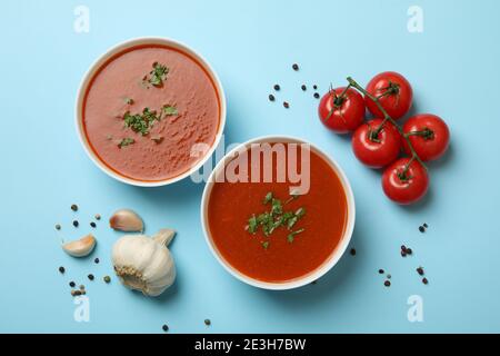Bowls with tomato soup and ingredients on blue background Stock Photo