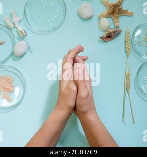 Creams and oils for the skin of hands, women's hands and a set of different ingredients. Eco-friendly and modern cosmetics, concept on a blue. Stock Photo