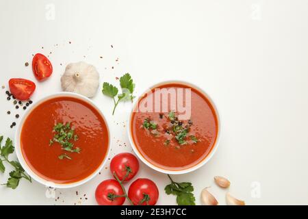 Bowls with tomato soup and ingredients on white background Stock Photo