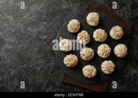 Tray with raw khinkali on kitchen towel on black smokey background Stock Photo
