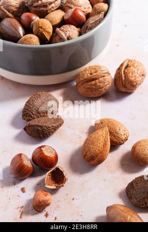 Assortment of mixed nuts in a bowl and a few cracked nuts on the side. Stock Photo