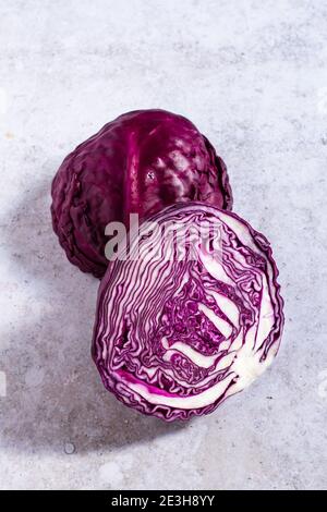Raw red cabbage sliced in half on a grey backdrop. Stock Photo