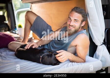 Man and his dog lying inside a camper van Stock Photo