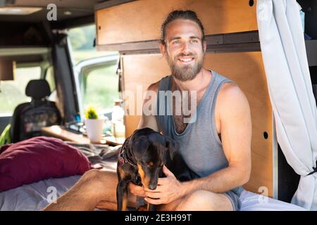 Smiling man and his dog inside a camper van Stock Photo