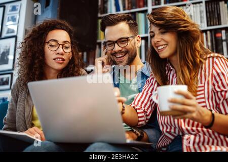University students in cooperation at library. Group of young friends reading books. Stock Photo