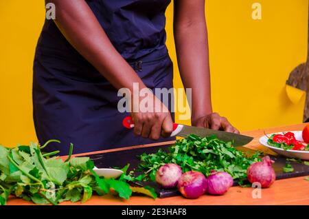 African chef carefully cutting vegetables with knife on the table Stock Photo