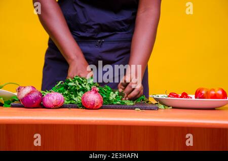 African chef carefully cutting vegetables with knife on the table Stock Photo