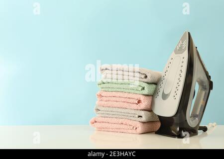 Modern iron and pile of towels on white table Stock Photo