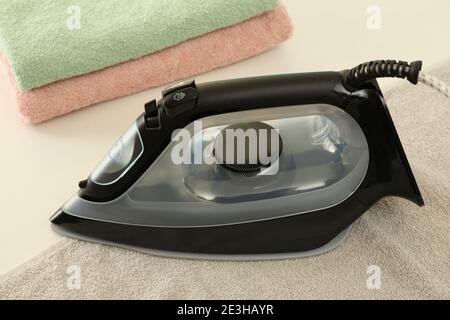 Modern iron and towels on white table, close up Stock Photo