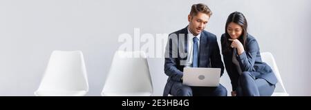 Smiling multiethnic businesspeople using laptop in hall, banner Stock Photo