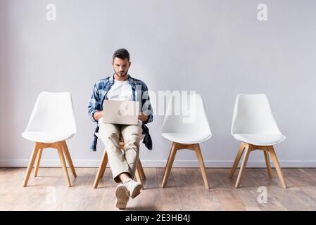 Freelancer in casual clothes using laptop in hall Stock Photo