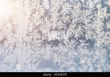 Frosty patterns on the window glass illuminated by the sun as a winter background Stock Photo