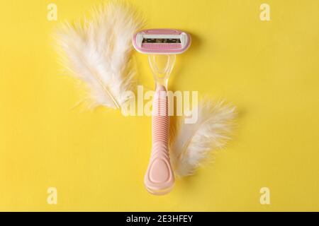 Razor and feathers on yellow background, place for text Stock Photo
