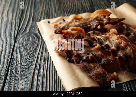 Baking paper with fried bacon on wooden background Stock Photo