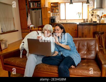 Happy couple and pet dog video calling friends using laptop. Man and woman online chatting celebrating easing of coronavirus restrictions. Hope and po Stock Photo
