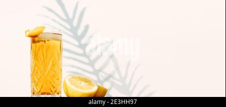 Banner with a glass of Ice Tea drink isolated against a white wall with plant shadows Stock Photo