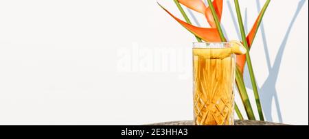 Banner with a glass of Ice Tea drink isolated against a white wall with plant shadows Stock Photo