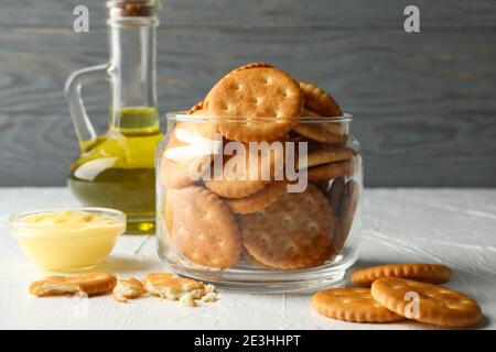Glass jar with crackers, sauce and oil on white table Stock Photo